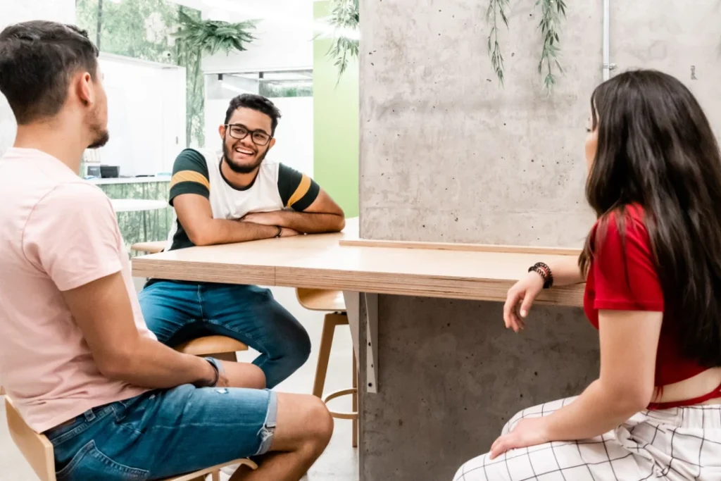 Three students talking to each other and laughing while sitting on campus