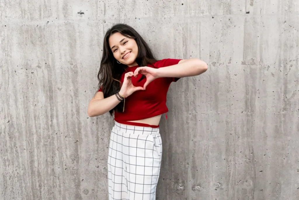 Girl wearing a red shirt making a heart with her hands